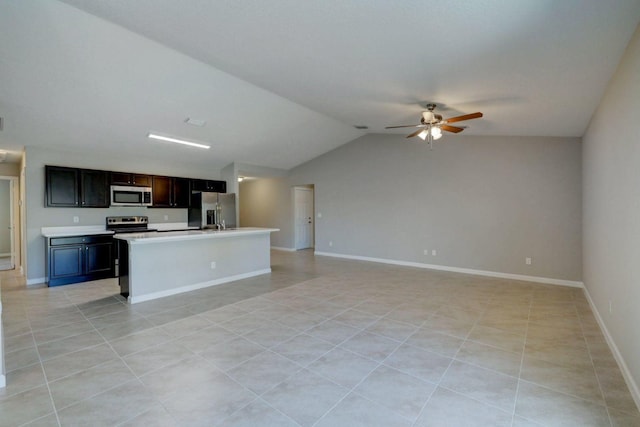 kitchen featuring ceiling fan, lofted ceiling, a center island with sink, light tile patterned flooring, and appliances with stainless steel finishes