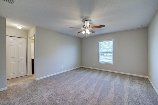 carpeted spare room featuring a textured ceiling and ceiling fan