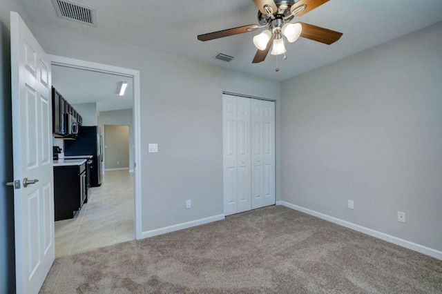 unfurnished bedroom featuring ceiling fan, a closet, and light carpet