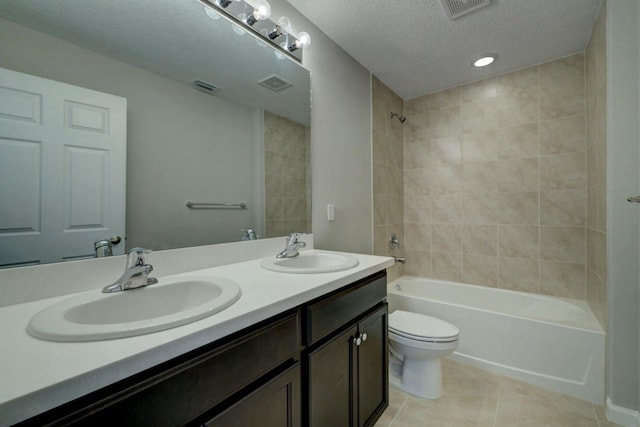 full bathroom with vanity, a textured ceiling, tiled shower / bath combo, tile patterned flooring, and toilet