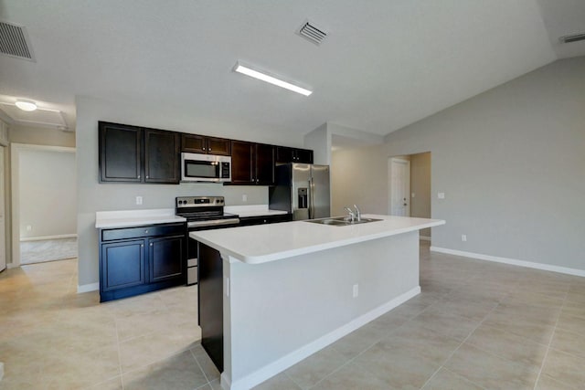 kitchen with appliances with stainless steel finishes, sink, light tile patterned floors, and an island with sink