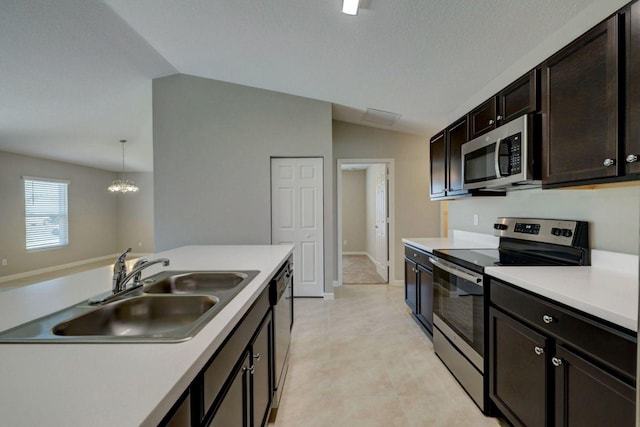 kitchen with decorative light fixtures, sink, appliances with stainless steel finishes, and vaulted ceiling