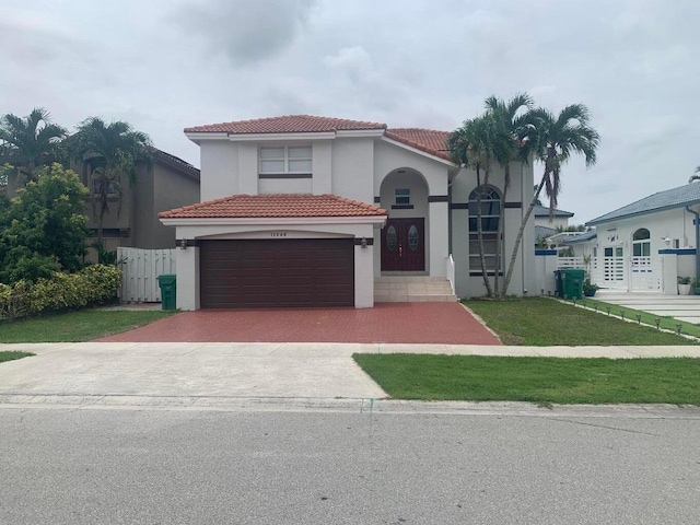 mediterranean / spanish home featuring a front yard and a garage