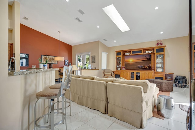 tiled living room with sink and vaulted ceiling with skylight