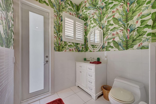 bathroom with tile patterned floors, toilet, sink, and tile walls