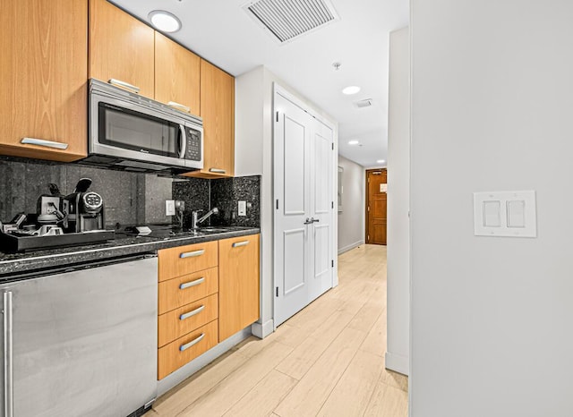 kitchen featuring decorative backsplash and dark stone countertops