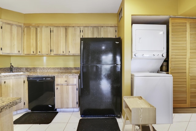 kitchen featuring stacked washer / drying machine, light brown cabinetry, sink, light tile patterned floors, and black appliances