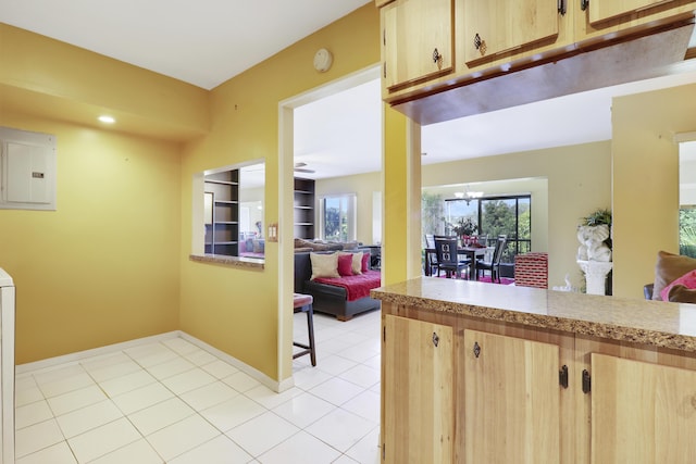 kitchen featuring light tile patterned flooring, light brown cabinetry, electric panel, and a chandelier