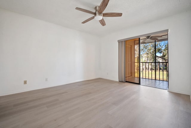 spare room featuring ceiling fan, light wood-type flooring, and a textured ceiling