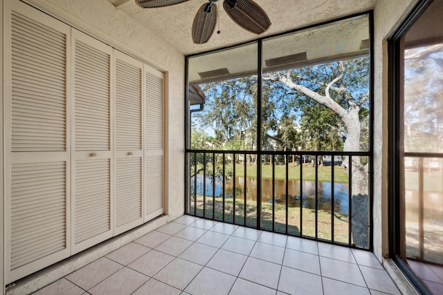 unfurnished sunroom with ceiling fan and a water view