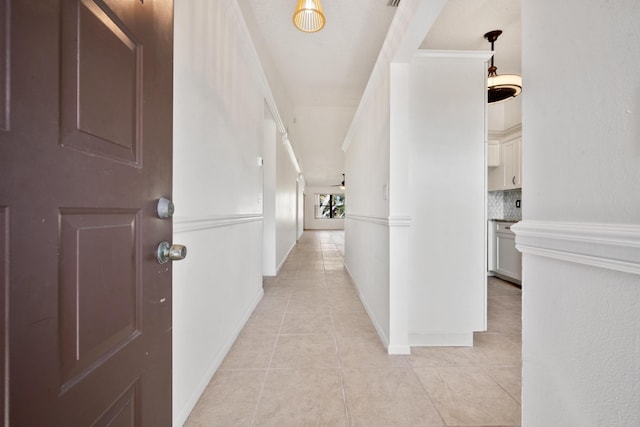 hallway featuring light tile patterned flooring and ornamental molding