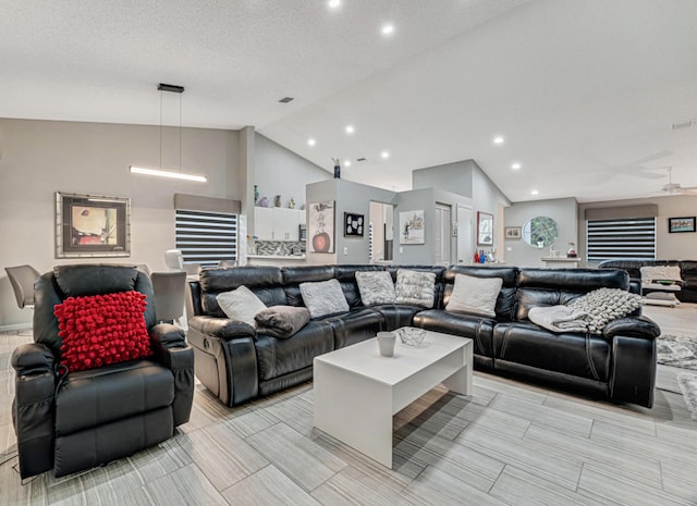 living room featuring ceiling fan, lofted ceiling, and a textured ceiling