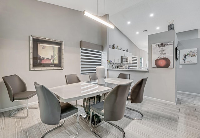 dining area featuring light hardwood / wood-style flooring and high vaulted ceiling