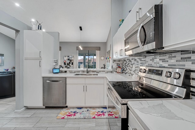 kitchen featuring stainless steel appliances, vaulted ceiling, sink, decorative light fixtures, and white cabinetry