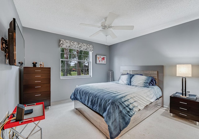 bedroom with a textured ceiling, ceiling fan, and light carpet