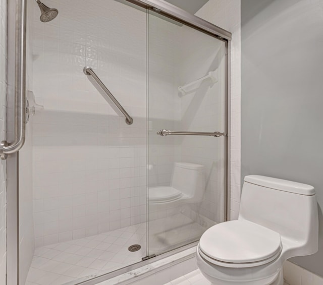 bathroom featuring toilet and a shower with shower door