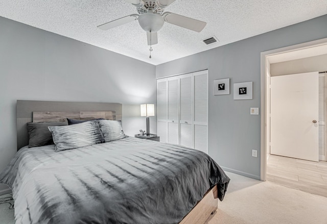 bedroom featuring a textured ceiling, a closet, ceiling fan, and light colored carpet