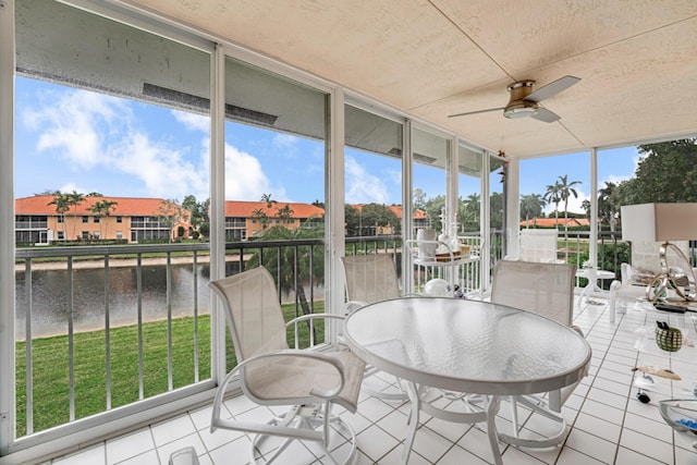 sunroom / solarium featuring ceiling fan and a water view