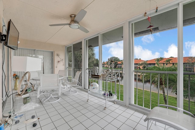 unfurnished sunroom with ceiling fan, a healthy amount of sunlight, and a water view