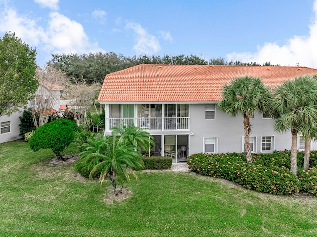 rear view of house featuring a lawn and a sunroom