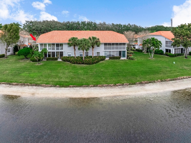 view of front of house with a sunroom, a water view, and a front yard