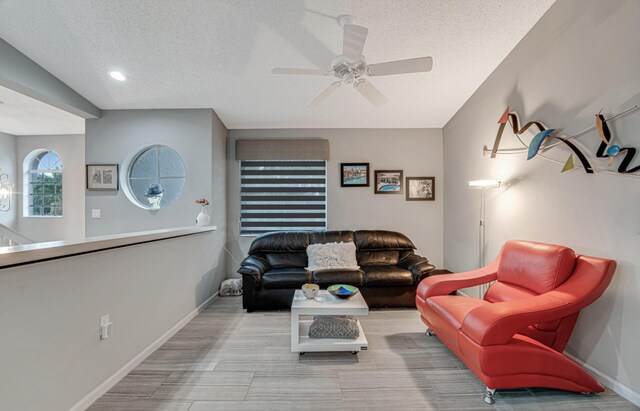 living room with ceiling fan and a textured ceiling