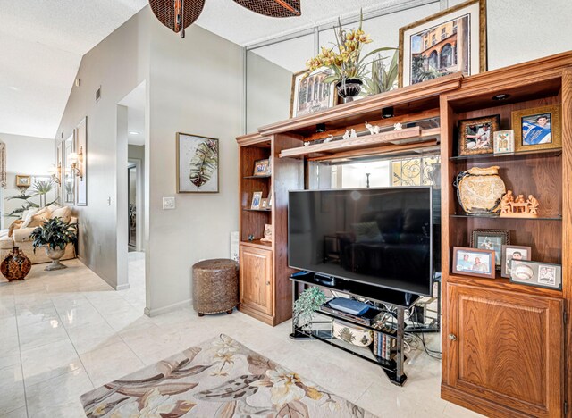 living room with a textured ceiling, ceiling fan, and light tile patterned floors