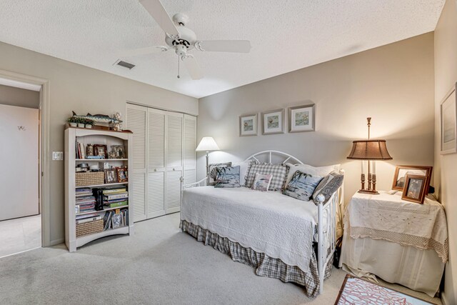 carpeted bedroom with ceiling fan and a textured ceiling