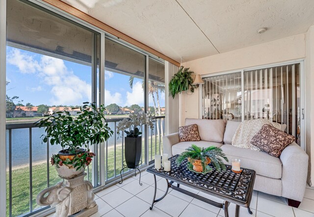 sunroom / solarium with plenty of natural light, ceiling fan, and a water view