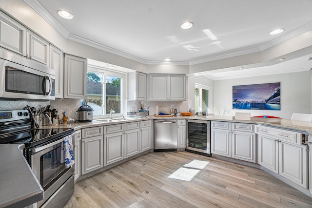 kitchen featuring beverage cooler, light hardwood / wood-style floors, appliances with stainless steel finishes, and tasteful backsplash