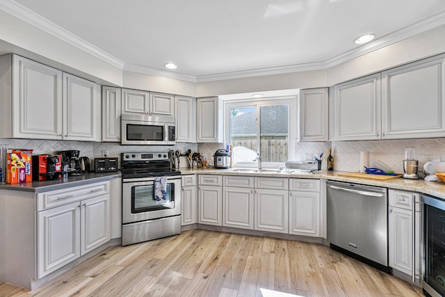 kitchen featuring sink, beverage cooler, backsplash, light hardwood / wood-style floors, and appliances with stainless steel finishes