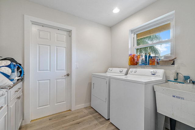 laundry room featuring cabinets, sink, light hardwood / wood-style floors, and washing machine and clothes dryer