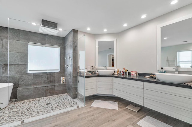 bathroom with tiled shower, hardwood / wood-style floors, and vanity