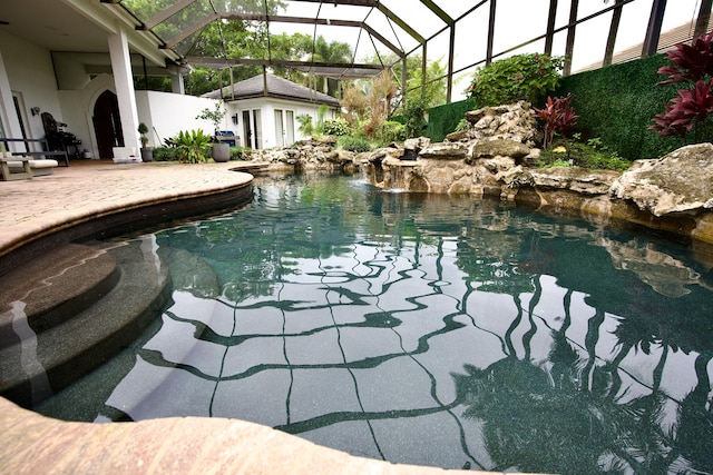 view of swimming pool with a patio, pool water feature, and glass enclosure