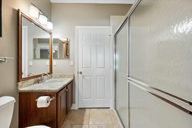 bathroom featuring vanity, toilet, and a shower with shower door