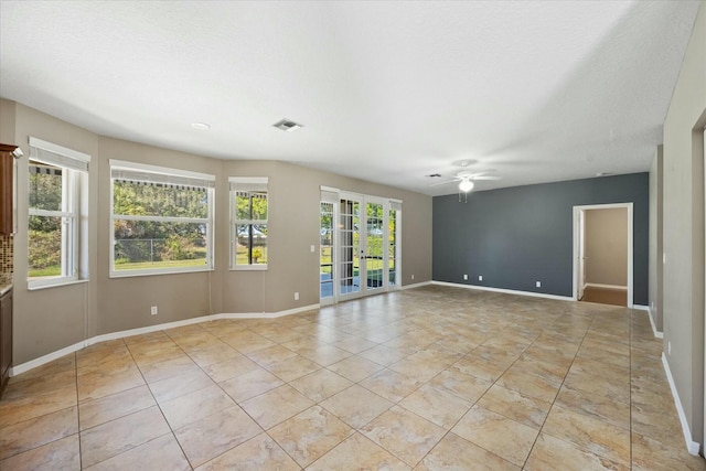 empty room with ceiling fan, french doors, light tile patterned floors, and a textured ceiling