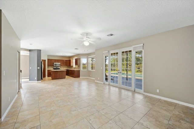 unfurnished living room featuring ceiling fan, light tile patterned floors, a textured ceiling, and french doors