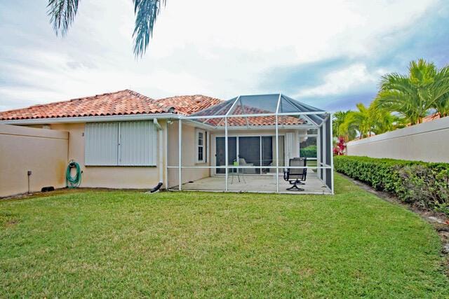 rear view of property featuring a lanai, a patio, and a yard