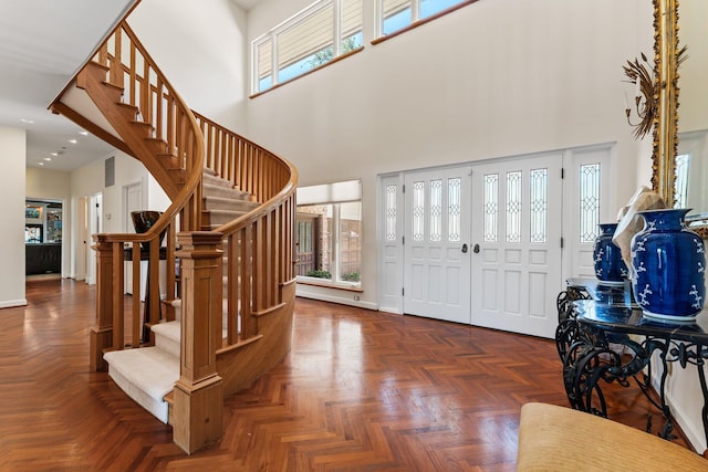 foyer entrance featuring baseboards, a high ceiling, and stairs