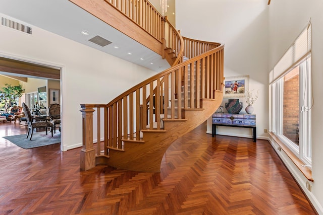 stairs featuring recessed lighting, visible vents, a towering ceiling, and baseboards