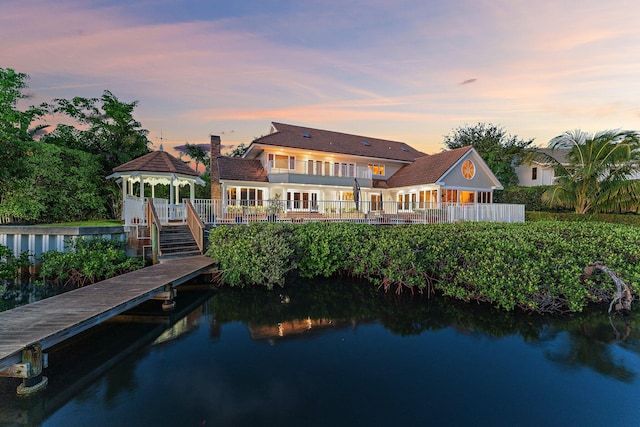 rear view of house with a gazebo, a water view, and a chimney