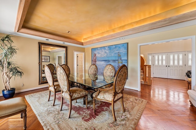 dining room featuring a raised ceiling and baseboards