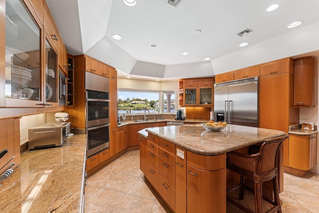 kitchen with a center island, brown cabinets, stainless steel appliances, and a sink