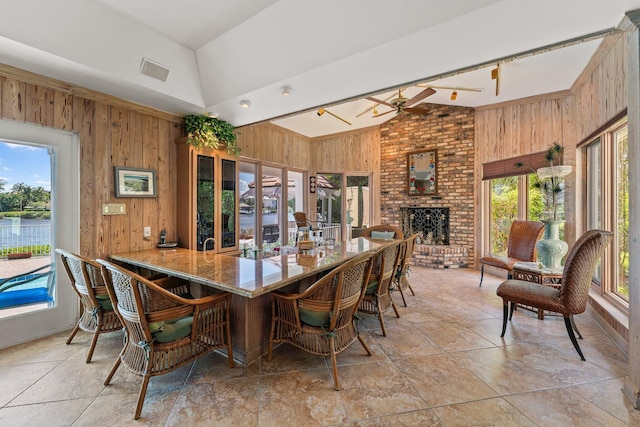 dining area featuring visible vents, a brick fireplace, and wood walls