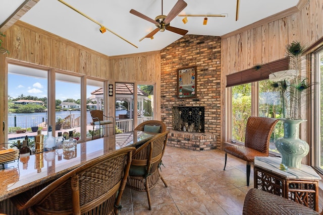 dining room featuring plenty of natural light, wooden walls, a brick fireplace, and vaulted ceiling