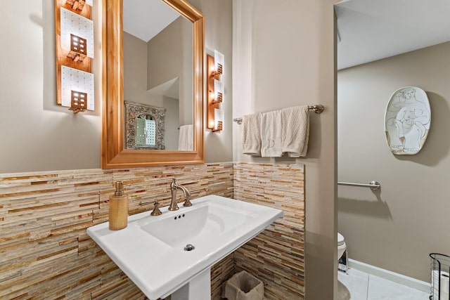 bathroom featuring tasteful backsplash, baseboards, toilet, tile patterned floors, and a sink