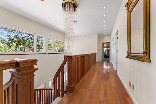 hall with visible vents, an upstairs landing, recessed lighting, an inviting chandelier, and light wood finished floors