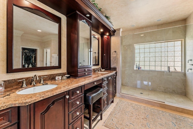 bathroom with a sink, a stall shower, and double vanity