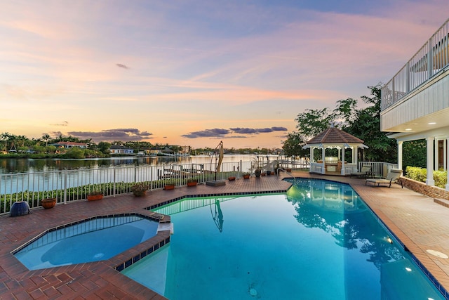 view of swimming pool with a gazebo, fence, a water view, and a pool with connected hot tub