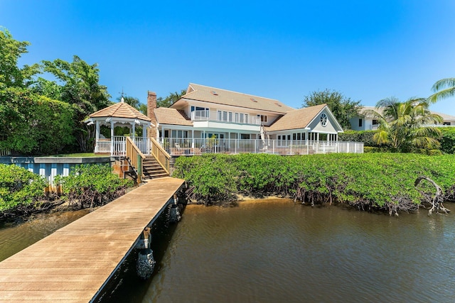 exterior space with a tile roof, a gazebo, a water view, and a chimney